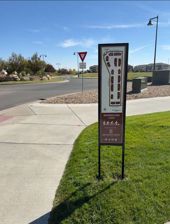 A signpost with a red triangle and a sign with a map of a loop.