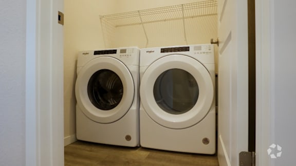 Two front loading washing machines in a small laundry room.