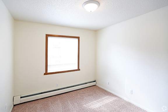 a bedroom with white walls and a window and carpet