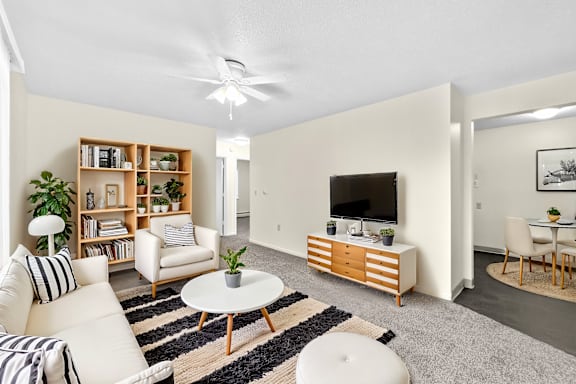 A living room with a white couch, a coffee table, and a television.