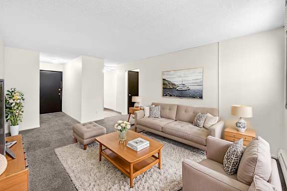 A living room with a grey couch and a painting on the wall.