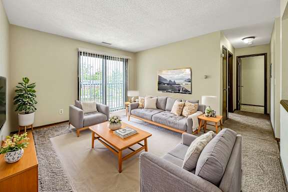 A living room with a grey couch, a wooden coffee table, and a painting on the wall.