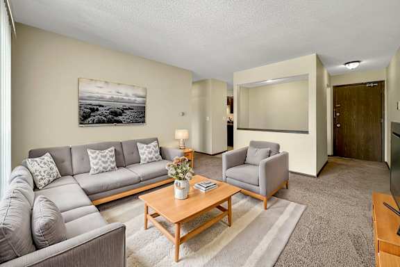 A living room with a grey couch, a wooden coffee table, and a painting on the wall.