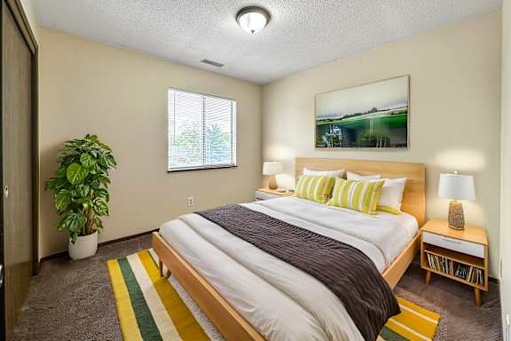 A bedroom with a large bed and a potted plant.
