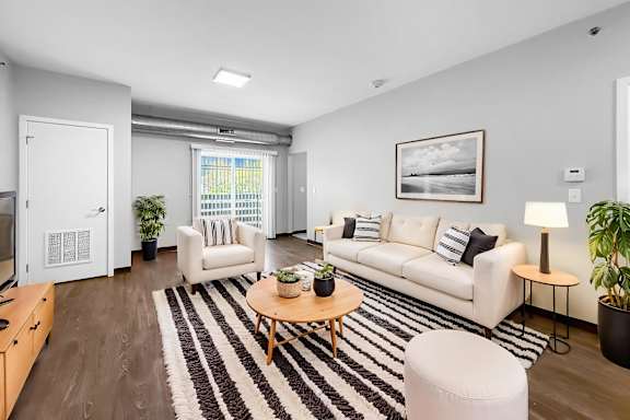 A living room with a white couch, a coffee table, and a rug.
