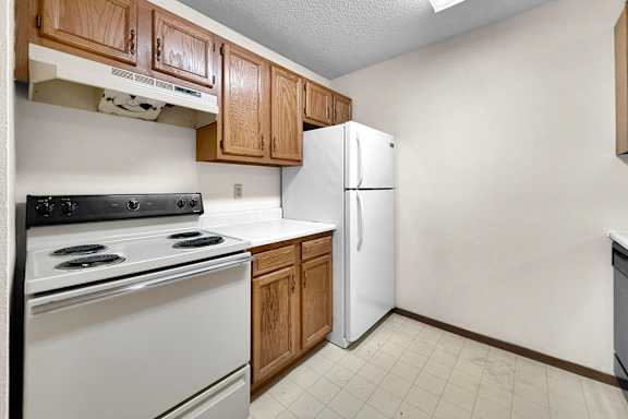 A kitchen with a white stove and refrigerator.