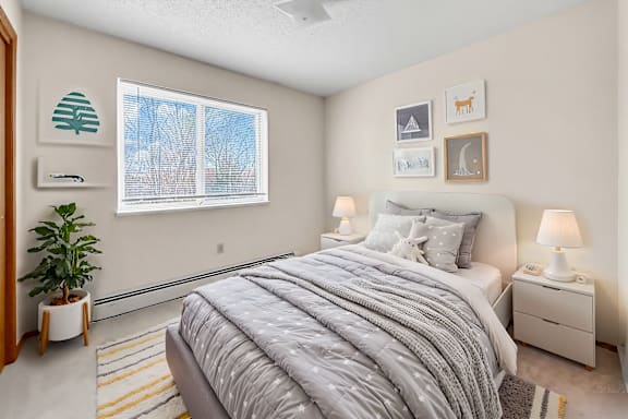 A bedroom with a large bed and a window with a view of a tree.