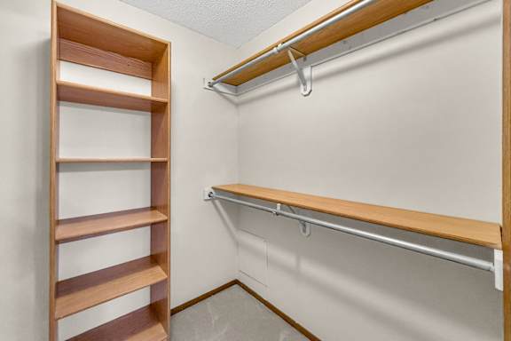 A wooden shelf with a metal rod is mounted on a white wall.