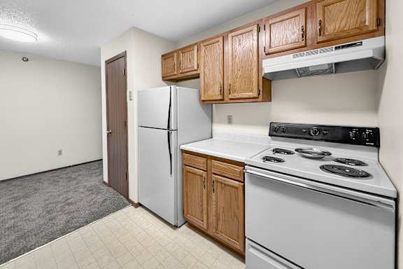 A kitchen with a white stove and a white refrigerator.