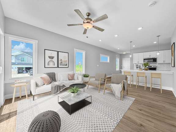 A modern living room with a white sofa, a coffee table, and a ceiling fan.