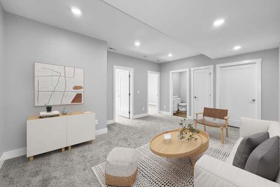 A modern living room with a grey carpet and white walls.