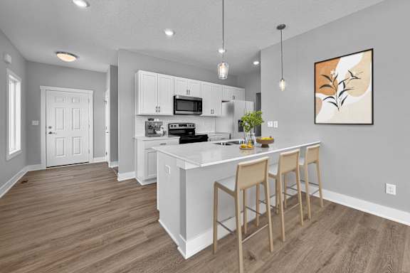 A kitchen with a white island and bar stools.