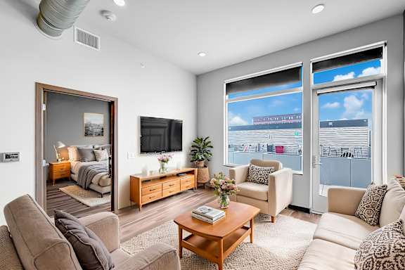 A living room with a brown couch, a wooden coffee table, and a large window with a view of the city.
