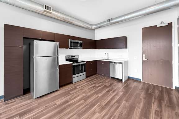 A kitchen with a refrigerator, oven, and microwave.