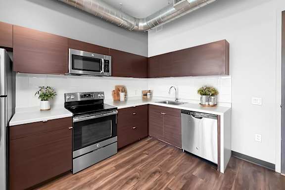 A modern kitchen with dark wood floors and stainless steel appliances.
