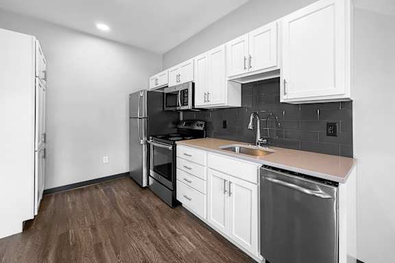 A kitchen with white cabinets and a black refrigerator.