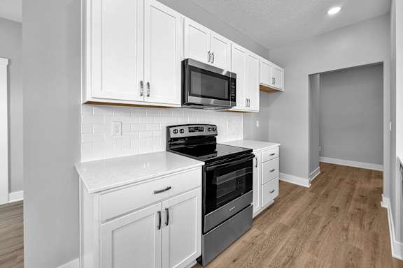 A kitchen with white cabinets and black appliances.