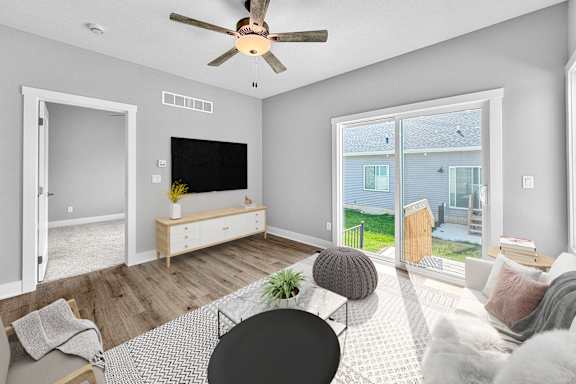 A living room with a television, a chair, a table, and a window.