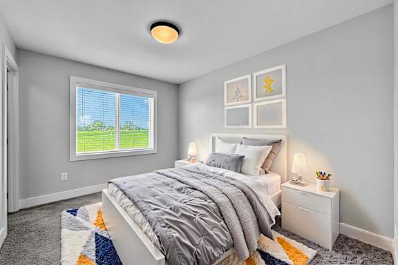 A bedroom with a large bed and a window showing a green lawn outside.