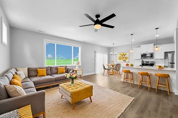 A living room with a grey couch and a yellow ottoman.
