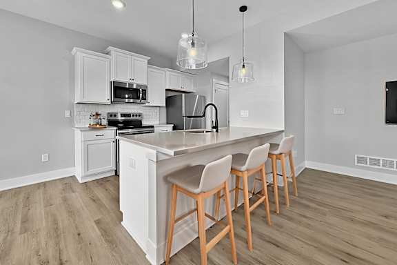 A kitchen with a white island and wooden chairs.