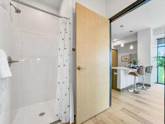 an open bathroom door leading to a shower with a curtain