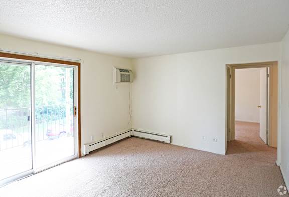an empty living room with white walls and a sliding glass door