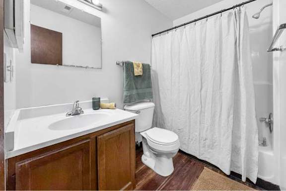 A white bathroom with a toilet, sink, and shower.