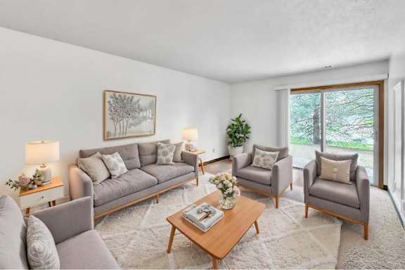 A living room with a grey couch, two armchairs, a coffee table, and a painting on the wall.