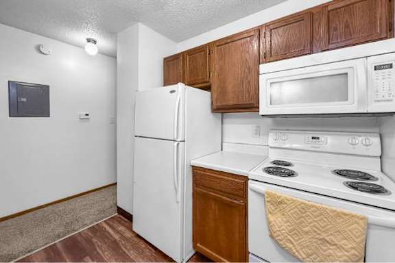 A kitchen with white appliances and brown cabinets.