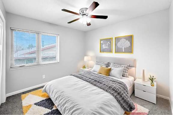 A bedroom with a large bed and a ceiling fan.
