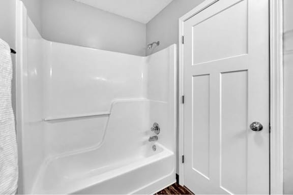 A white bathroom with a tub and a door.