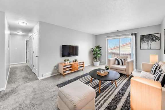 A living room with a flat screen TV mounted on the wall.