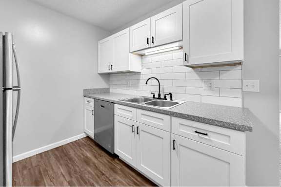 A kitchen with white cabinets and a granite countertop.