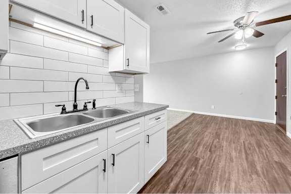 A kitchen with white cabinets and a wooden floor.