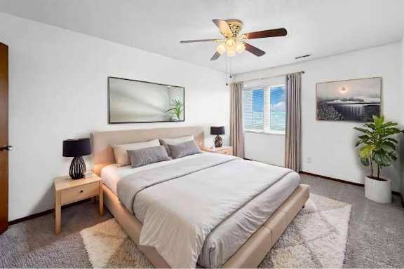 A bedroom with a large bed, a ceiling fan, and a window with a view of a waterfall.