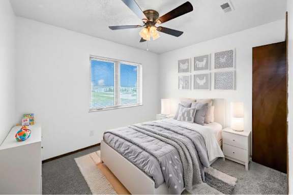 A bedroom with a bed, nightstand, and a ceiling fan.