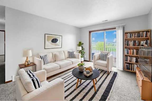 A living room with a white sofa, a black and white striped couch, a coffee table, and a bookshelf.