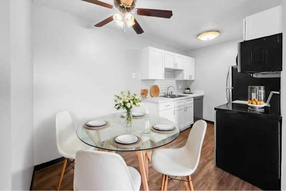 A modern kitchen with a glass dining table and white chairs.