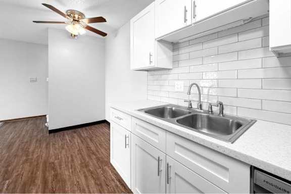A kitchen with white cabinets and a wooden floor.