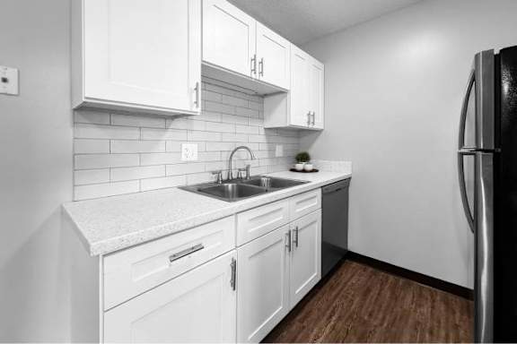 A kitchen with white cabinets and a black refrigerator.