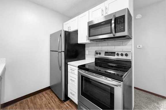 A black refrigerator and microwave in a kitchen.