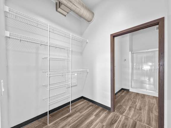 A walk-in closet with shelves and a door leading to another room.
