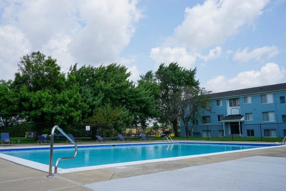 Swimming Pool Entry with pool chairs and apartment building, at Gale Gardens
