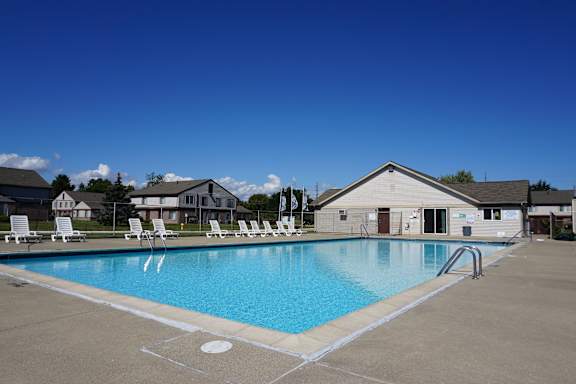 A large swimming pool with lounge chairs and a building in the background.