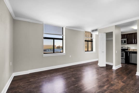an empty living room with a window and a kitchen