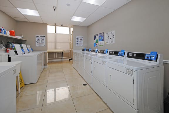 a row of washing machines in a laundry room with washers and dryers