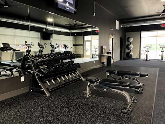 A gym with treadmills, elliptical machines, and a television.
