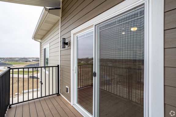 A sliding glass door with a screen on the balcony of a house.