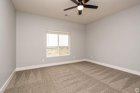 A room with a ceiling fan and a window overlooking a desert landscape.